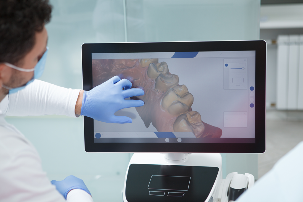 A dentist using a touchscreen display to analyze a 3D digital model of a patient's teeth, demonstrating the benefits of digital implant technology.